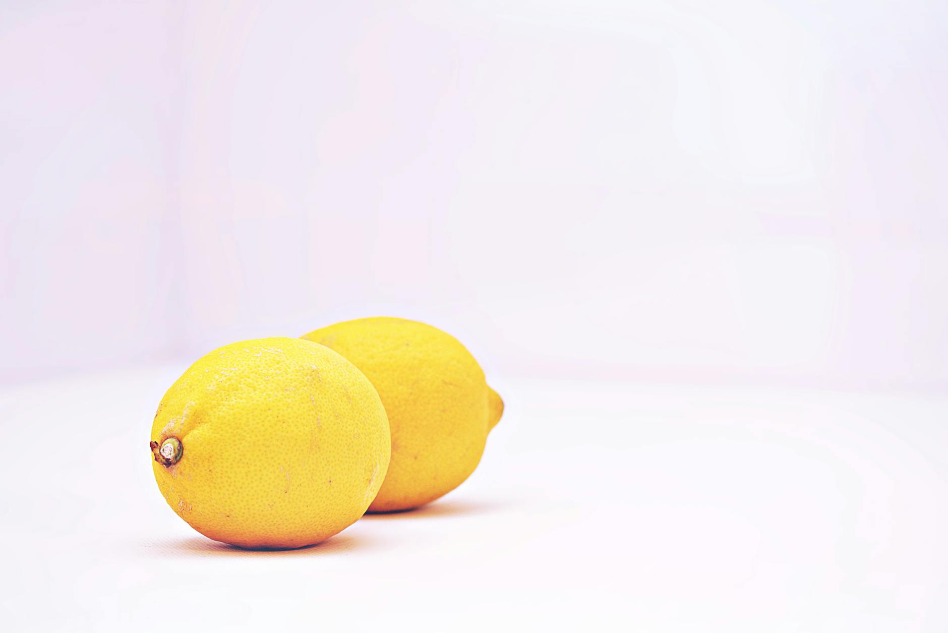 Two vibrant lemons against a minimalistic white background, symbolizing freshness and simplicity