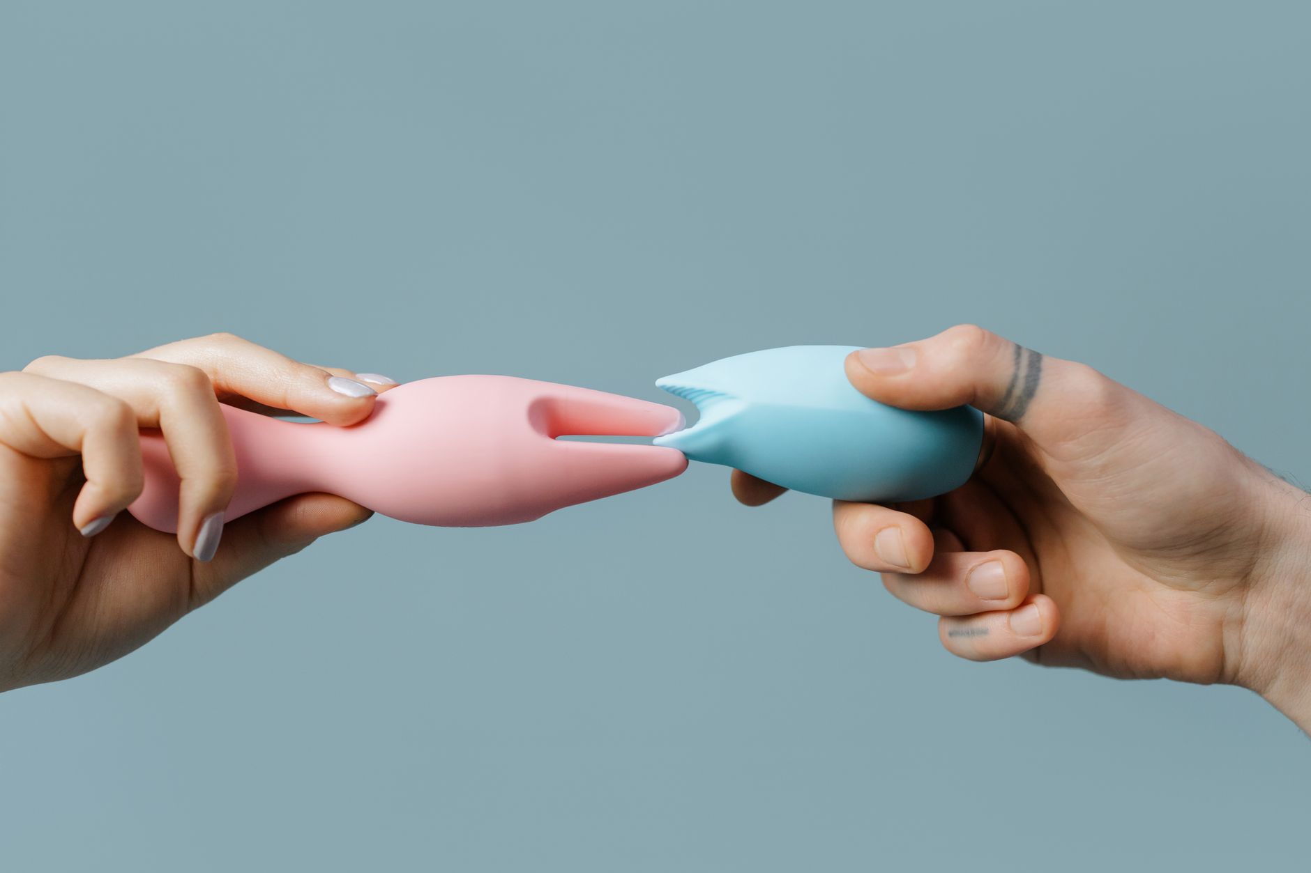 Hand holding an orange vibrator against a minimalist purple backdrop